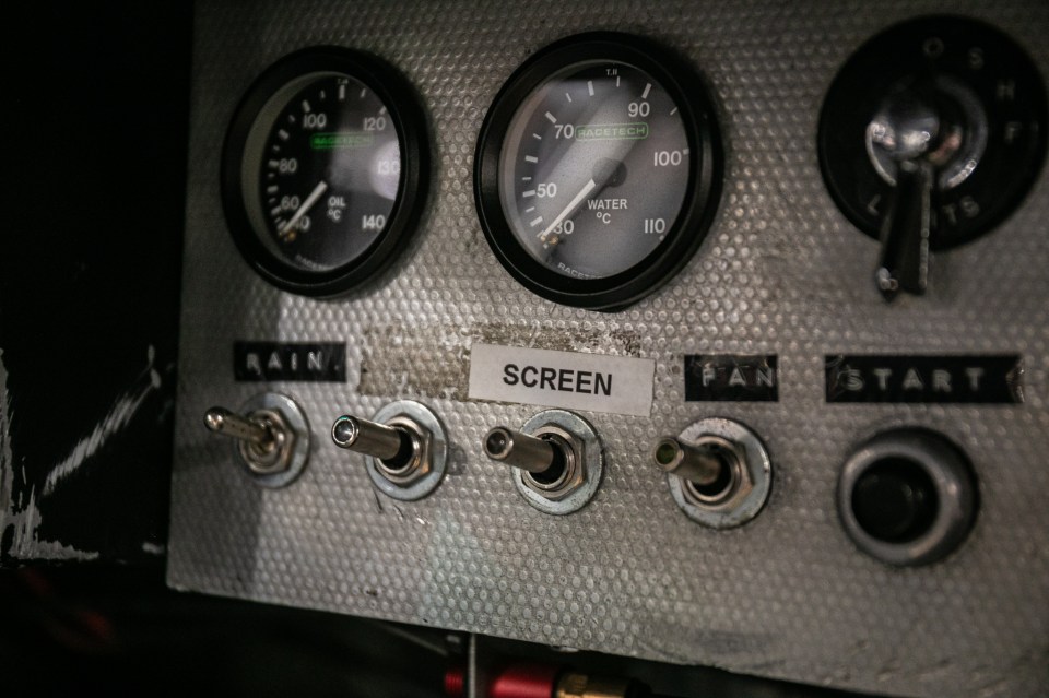 Close-up of a classic car's control panel with gauges and switches.