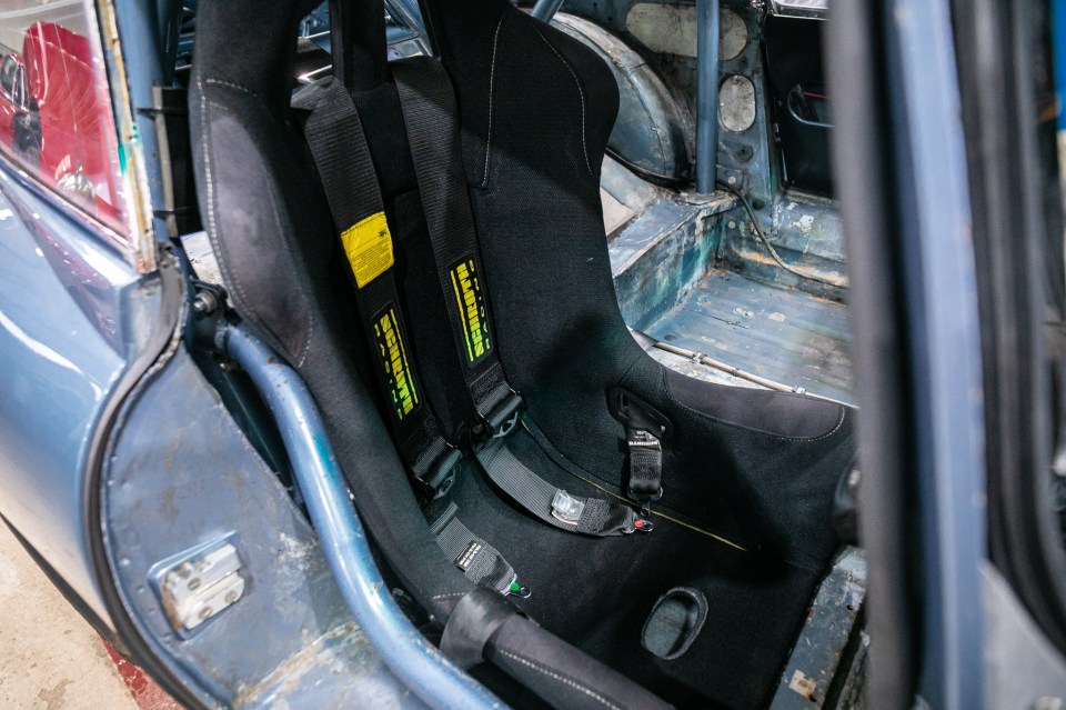 Interior view of a racing car's driver's seat with safety harnesses.