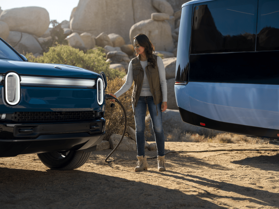 Woman charging an electric vehicle with an electric caravan.