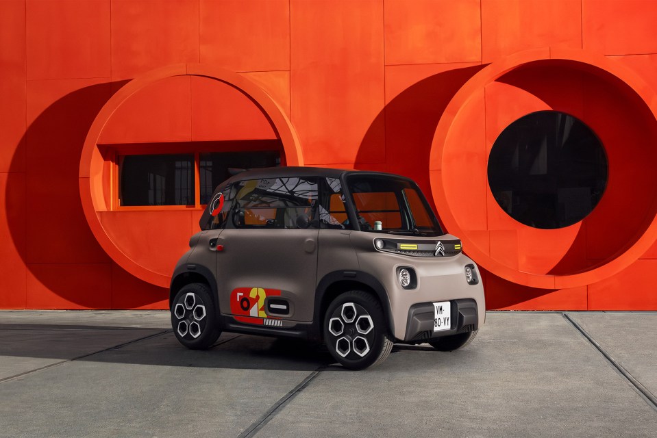 Citroen AMI electric car parked in front of an orange wall.