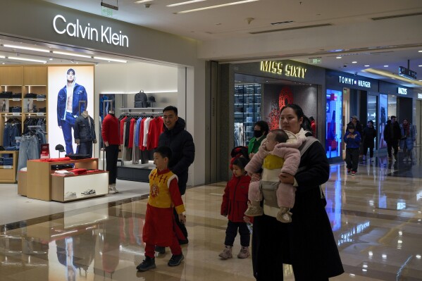 Shoppers tour by Calvin Klein and Tommy Hilfiger fashion boutiques, which are owned by PVH Group, at a shopping mall in Beijing, Tuesday, Feb. 4, 2025. (AP Photo/Andy Wong)