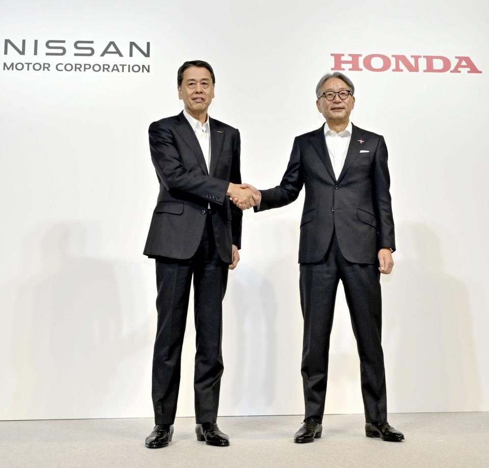 Nissan and Honda executives shaking hands at a press conference to announce a partnership to develop electric vehicles.