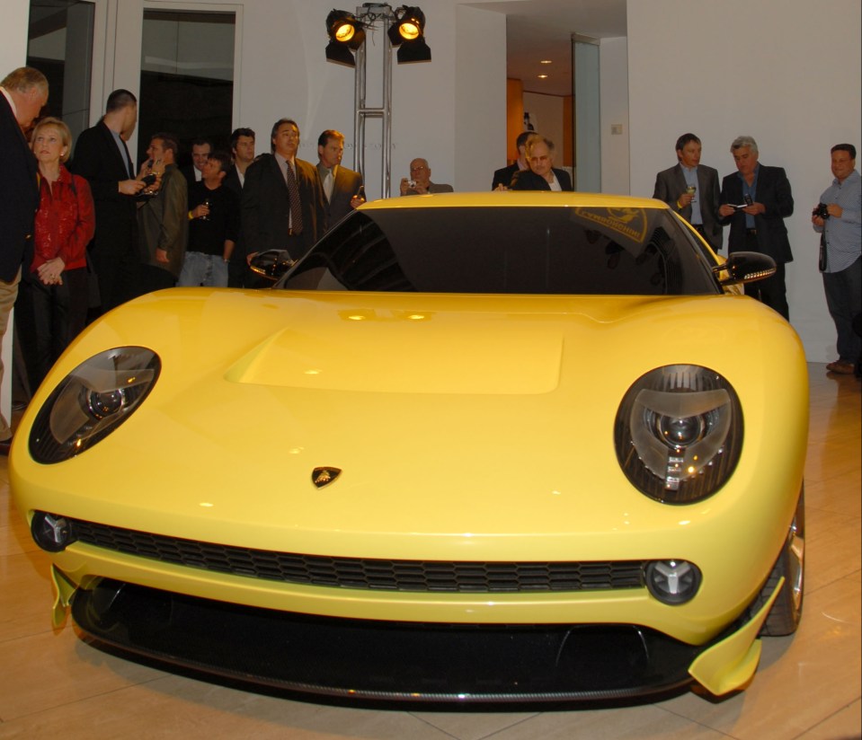 Yellow Lamborghini Miura concept car at a launch party.