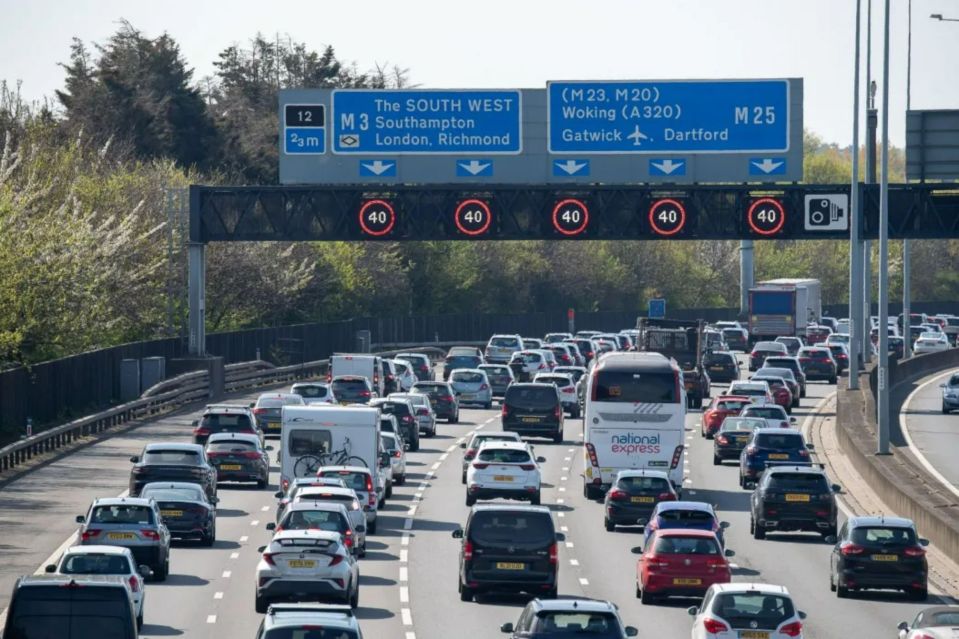 Heavy traffic on a highway with road signs indicating routes to Southampton, London, and Gatwick.