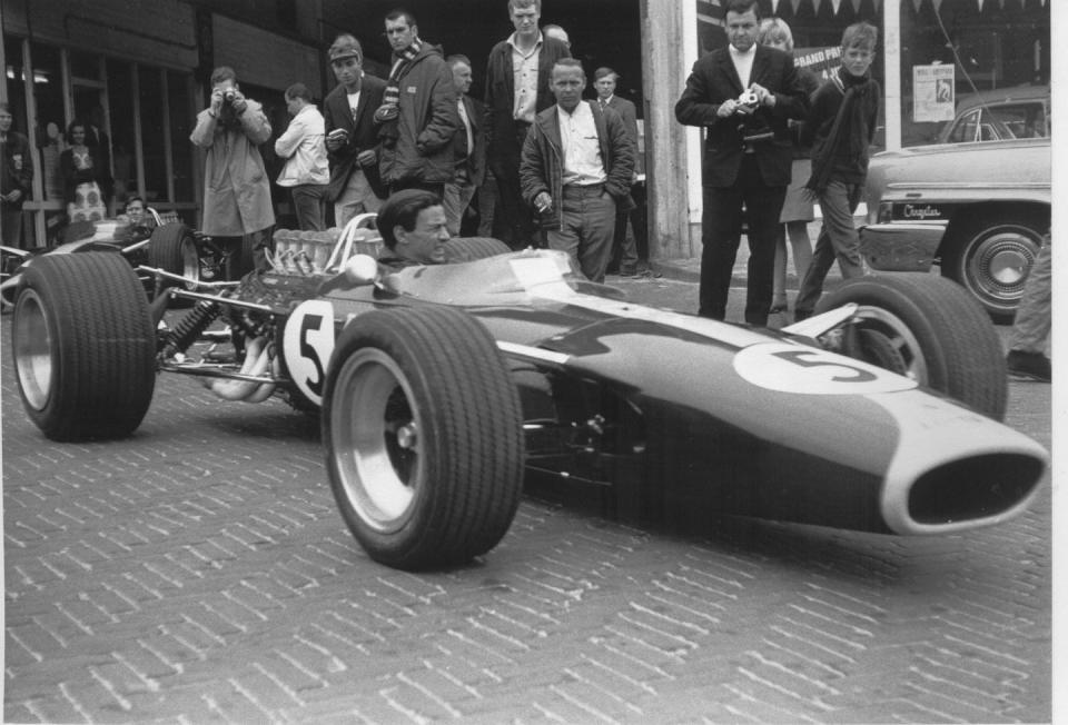 a vintage racing car parked in a public area with onlookers