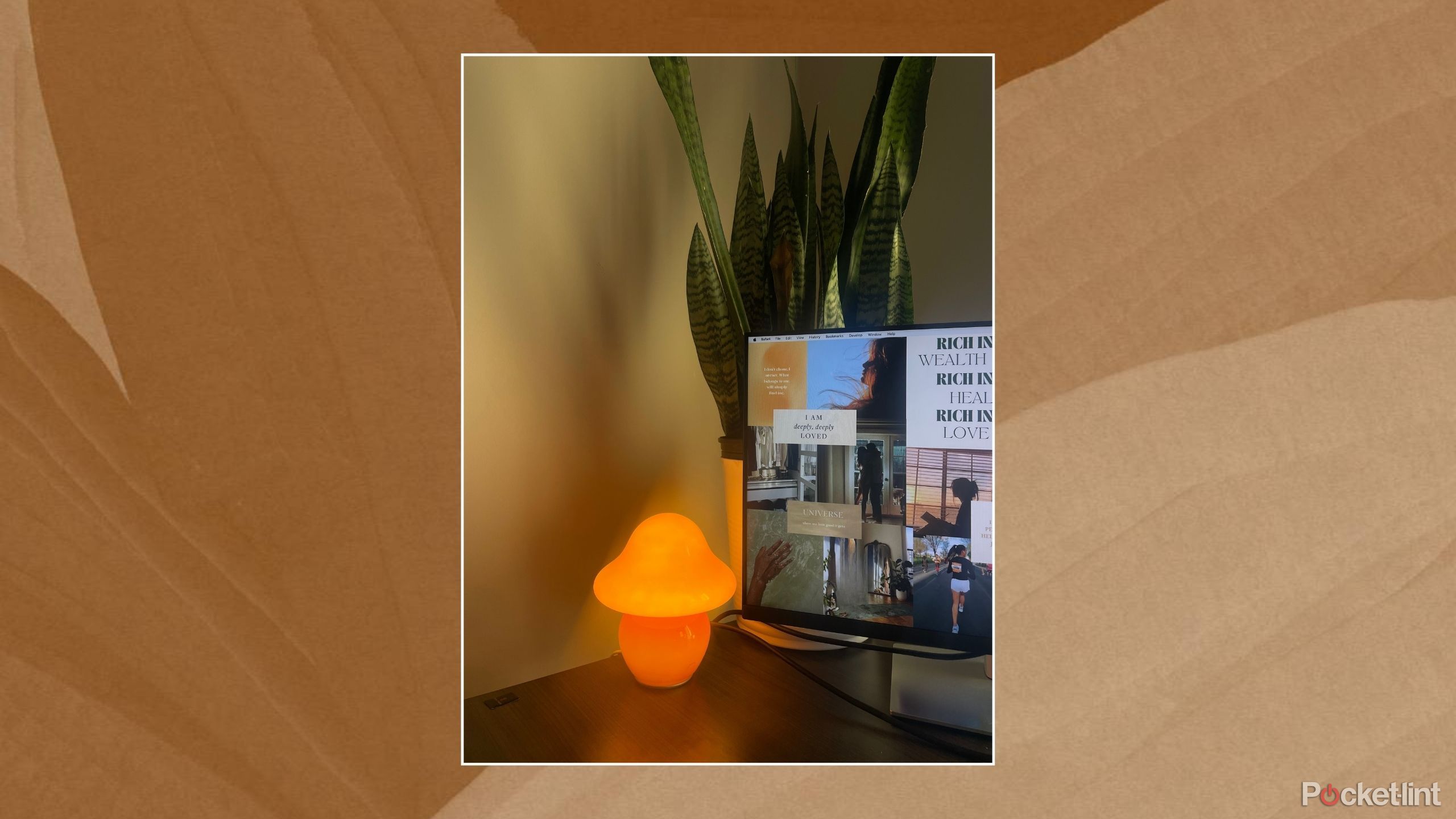 A desk shot of a mushroom lamp, monitor, and plant