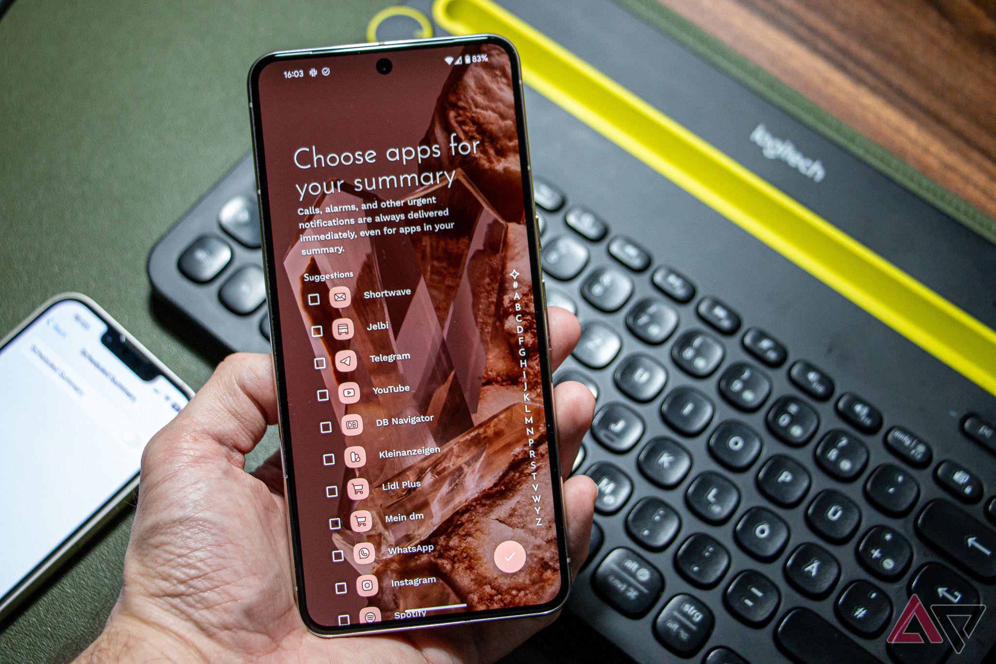 A Google Pixel 8 Pro held in hand, running Niagara Launcher's setup screen for notification summary, with a keyboard and an iPhone 13 visible in the background