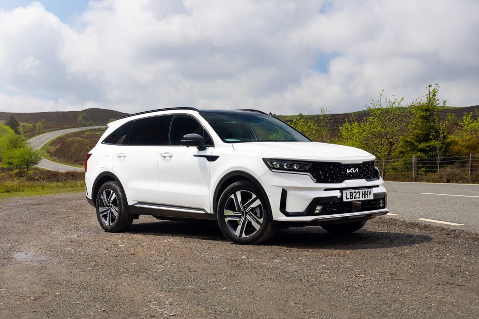 White Kia Sorento HEV parked near a road.