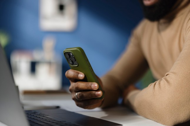 Close up of unrecognizable African American businessman text messaging on smart phone in the office.