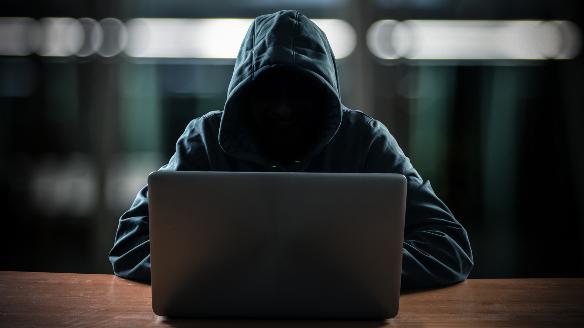 Hacker in front of his computer with a  dark face.