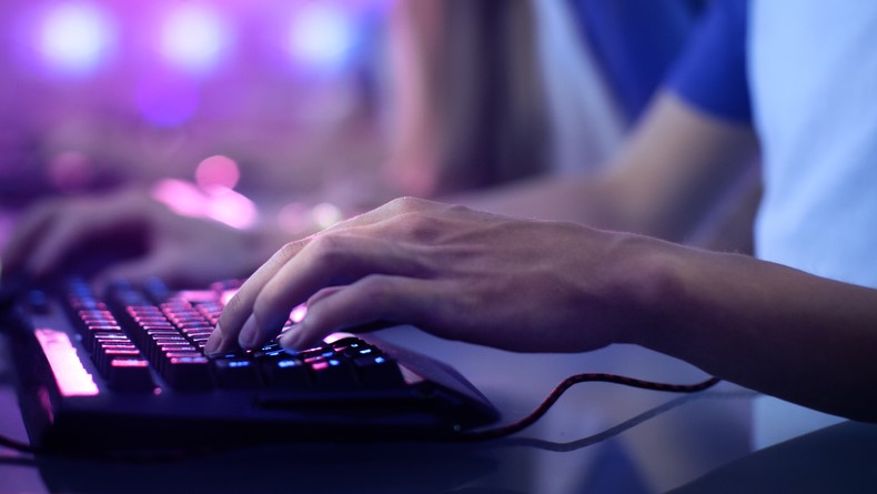 A PC gamer's hands on a backlit keyboard