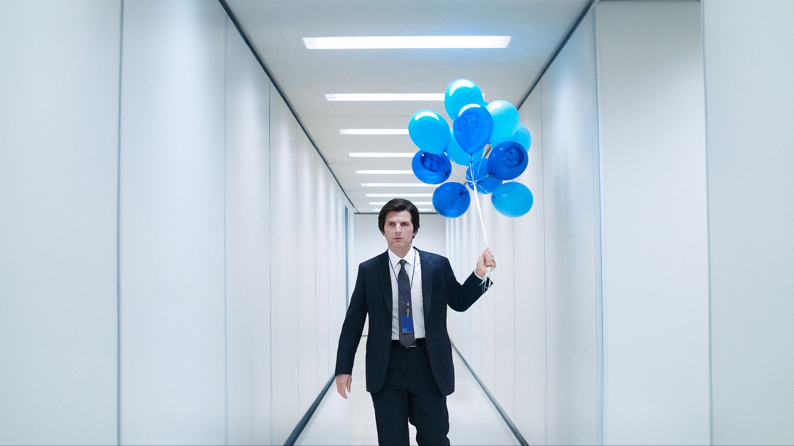 Severance still of a man holding blue balloons. 