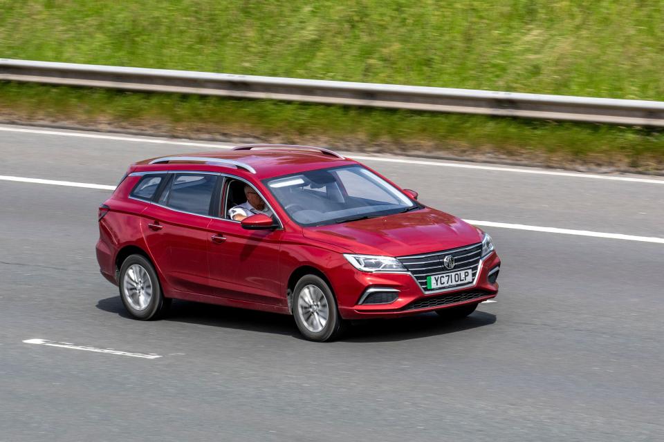 Red MG 5 EV driving on the M61 motorway.