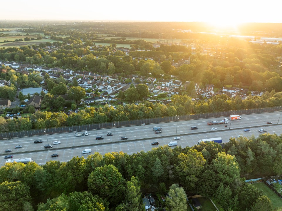 Aerial view of a multi-lane highway at sunrise, surrounded by English suburbs.