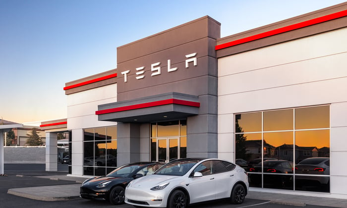 A Tesla dealership with two Tesla electric vehicles parked out front.