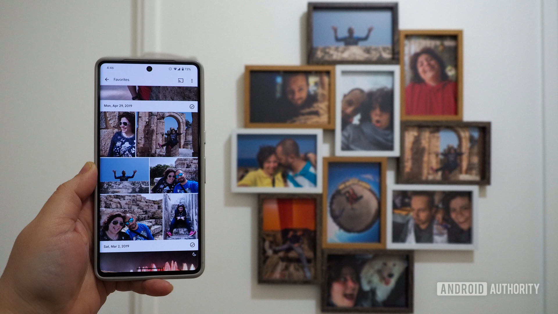 Hand holding a Pixel 7 Pro with Google Photos favorites grid, with a photo frame in the background that has Google Photos prints