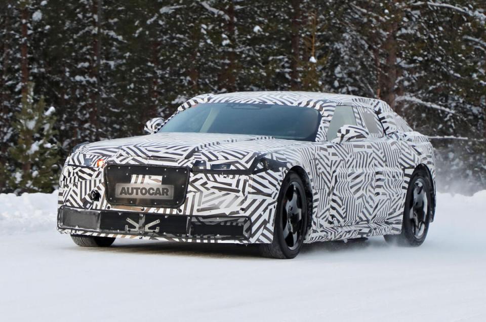 Camouflaged electric Jaguar GT car in winter setting.