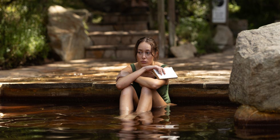 individual sitting in a water pool holding a book