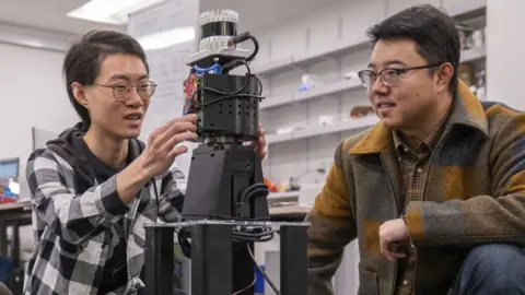 Sylvia Zhang Prof Mingmin Zhao and a student look at the robot