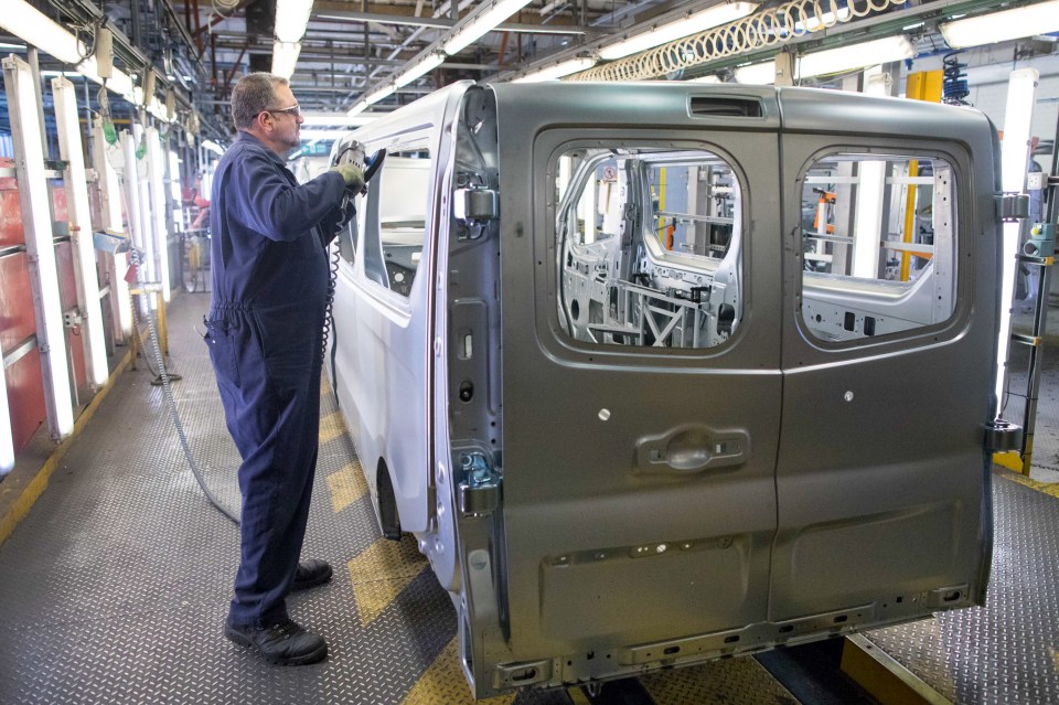 Factory worker smoothing the edges of a van window panel.