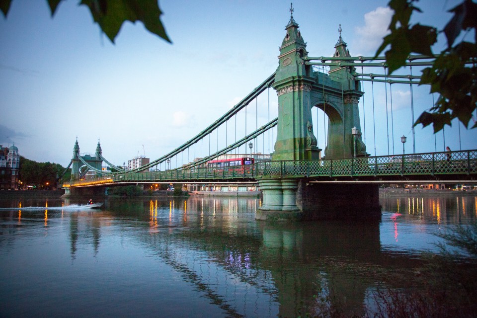 Hammersmith Bridge at sunset, with a bus crossing.