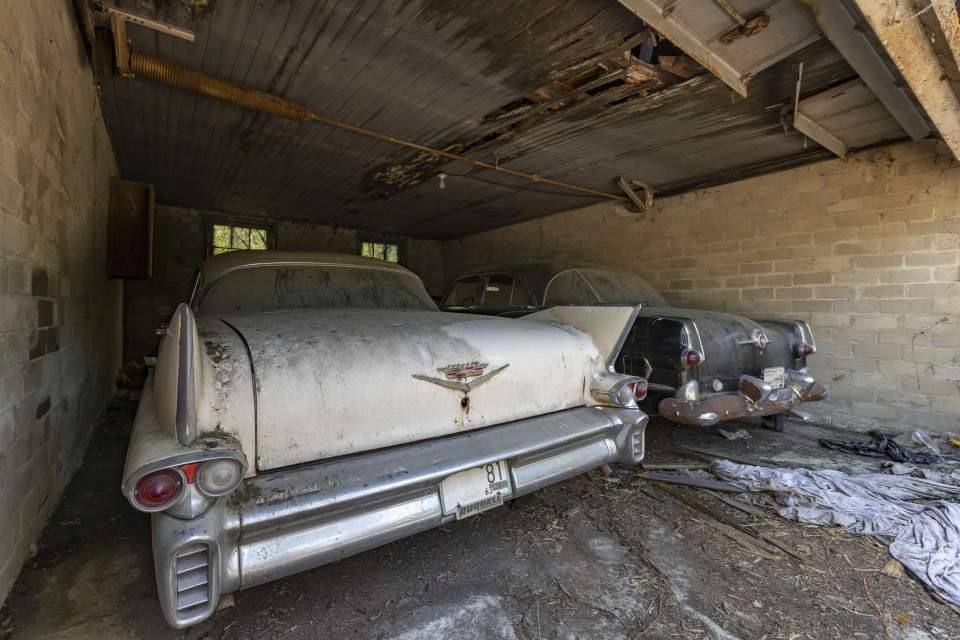 Dust-covered vintage cars in an abandoned garage.