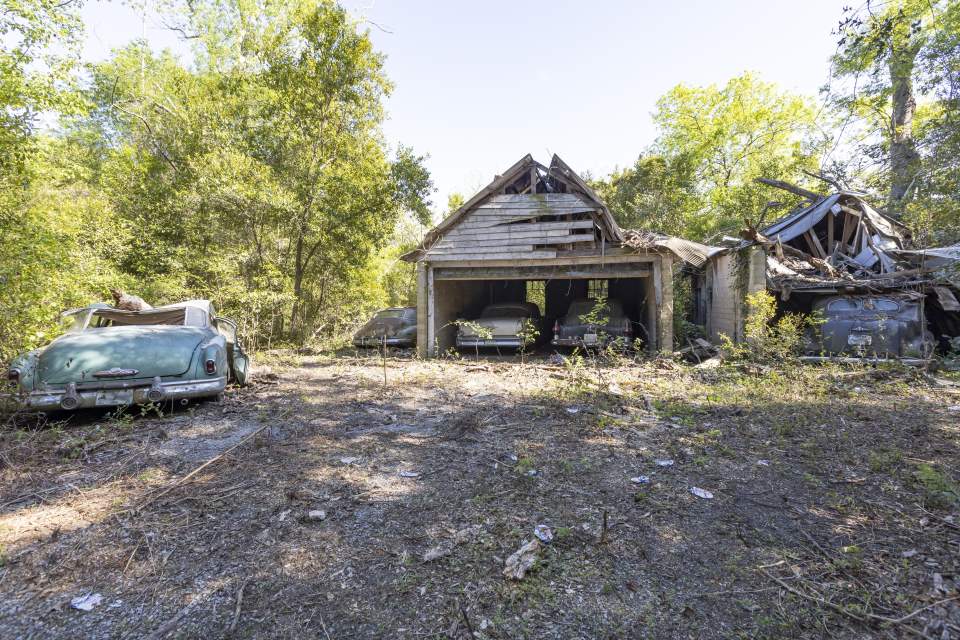 Abandoned vintage cars in a dilapidated garage.