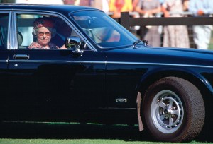 Queen Elizabeth II driving her Daimler-badged Jaguar to a polo match in 1995.