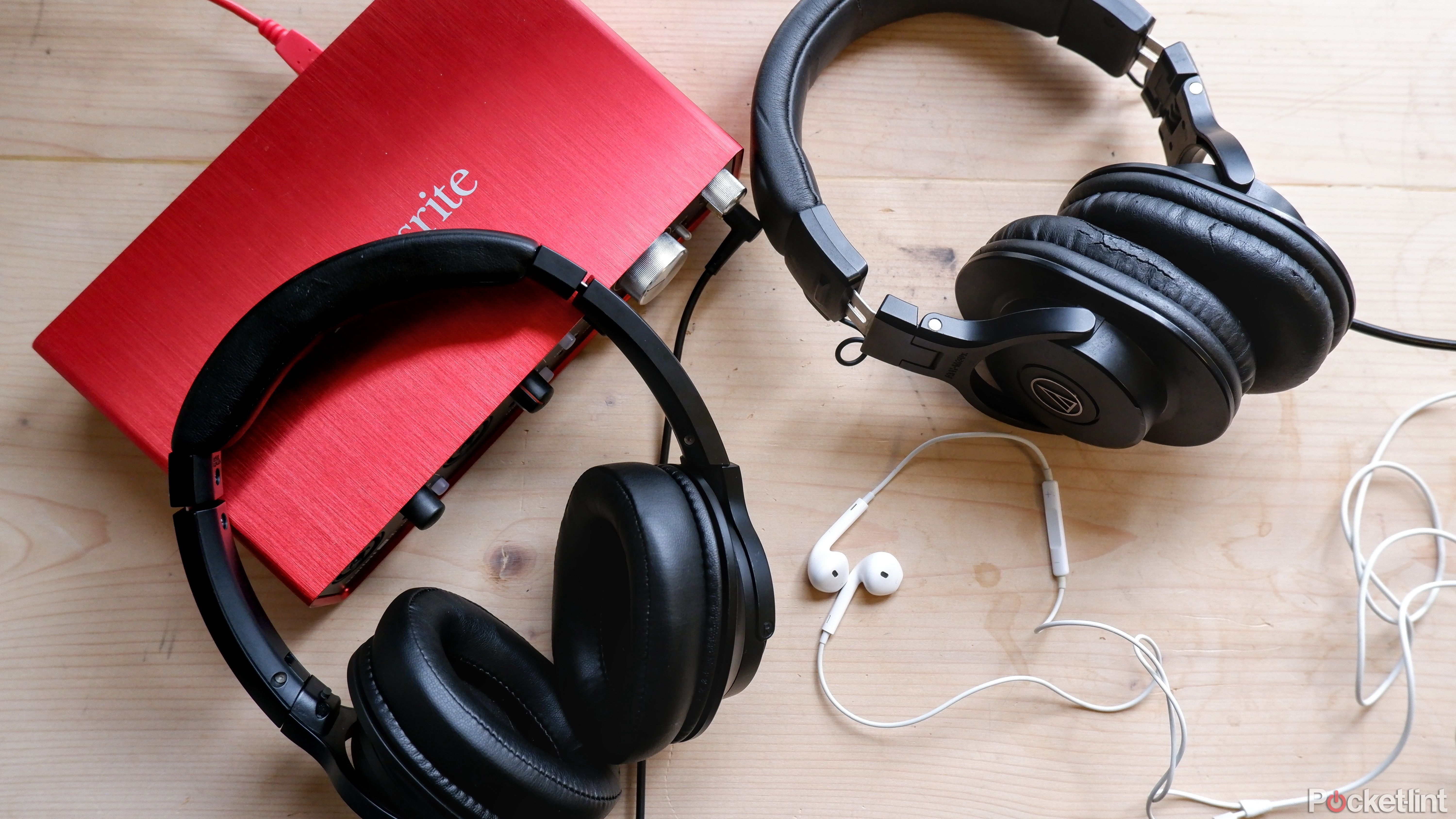 Wired headphones on a desk next to a Focusrite audio interface.