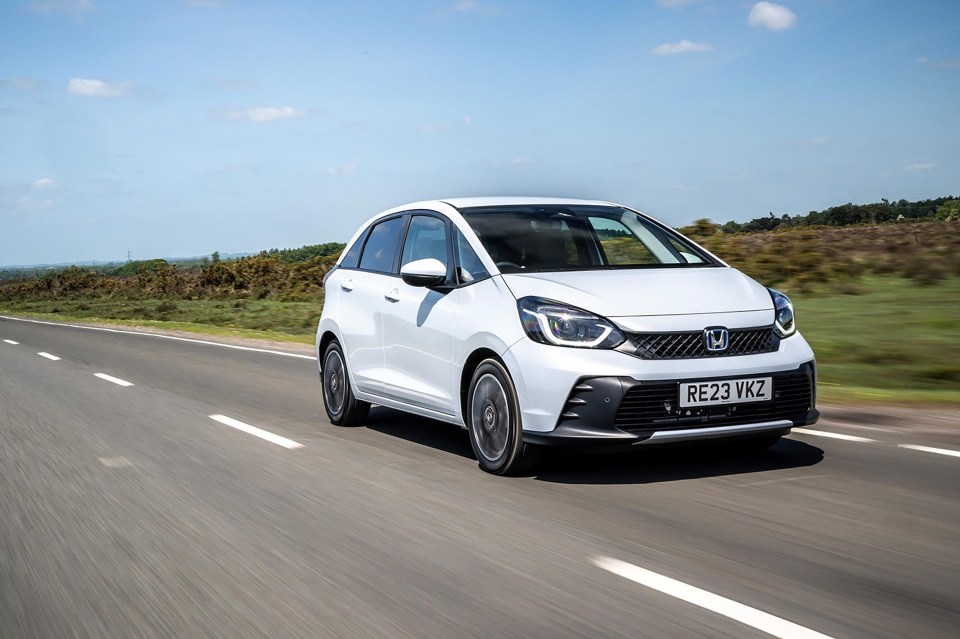 White Honda Jazz hybrid driving on a road.