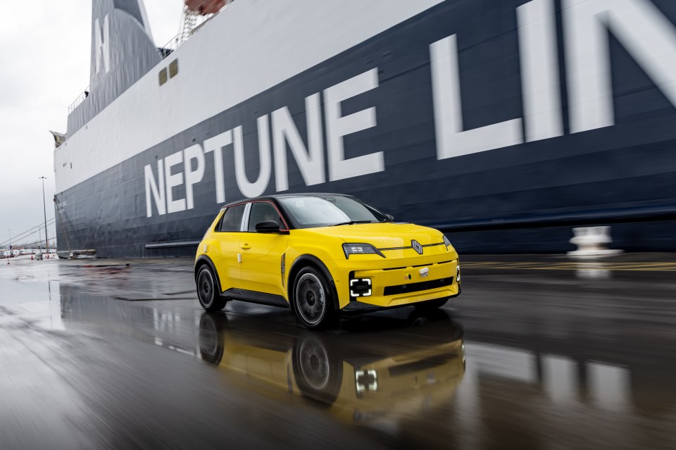 Yellow car driving past a ship.