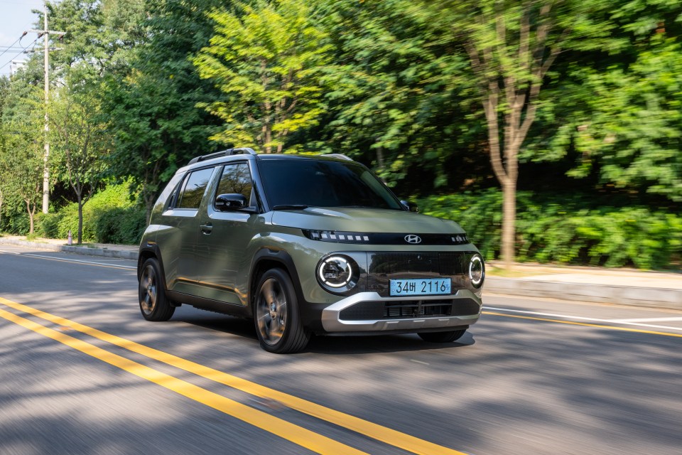 Green Hyundai Casper driving on a road.