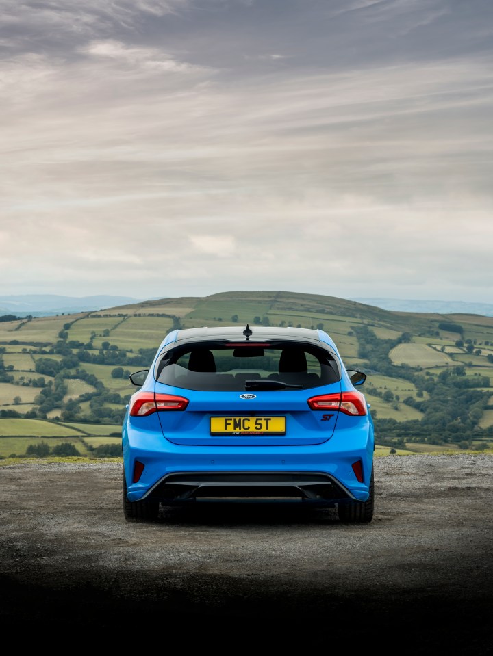 Rear view of a blue Ford Focus ST parked overlooking a valley.