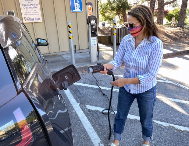 Faye Griffin of Mill Valley uses an electric vehicle charging station while her son plays soccer nearby at Hauke Park in Mill Valley, Calif. on Tuesday, May 4, 2021. (Sherry LaVars/Marin Independent Journal)