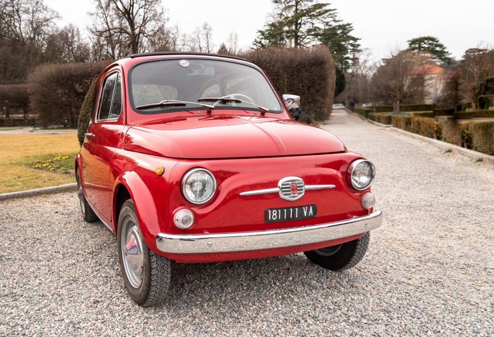 Red classic Fiat 500 parked outdoors.