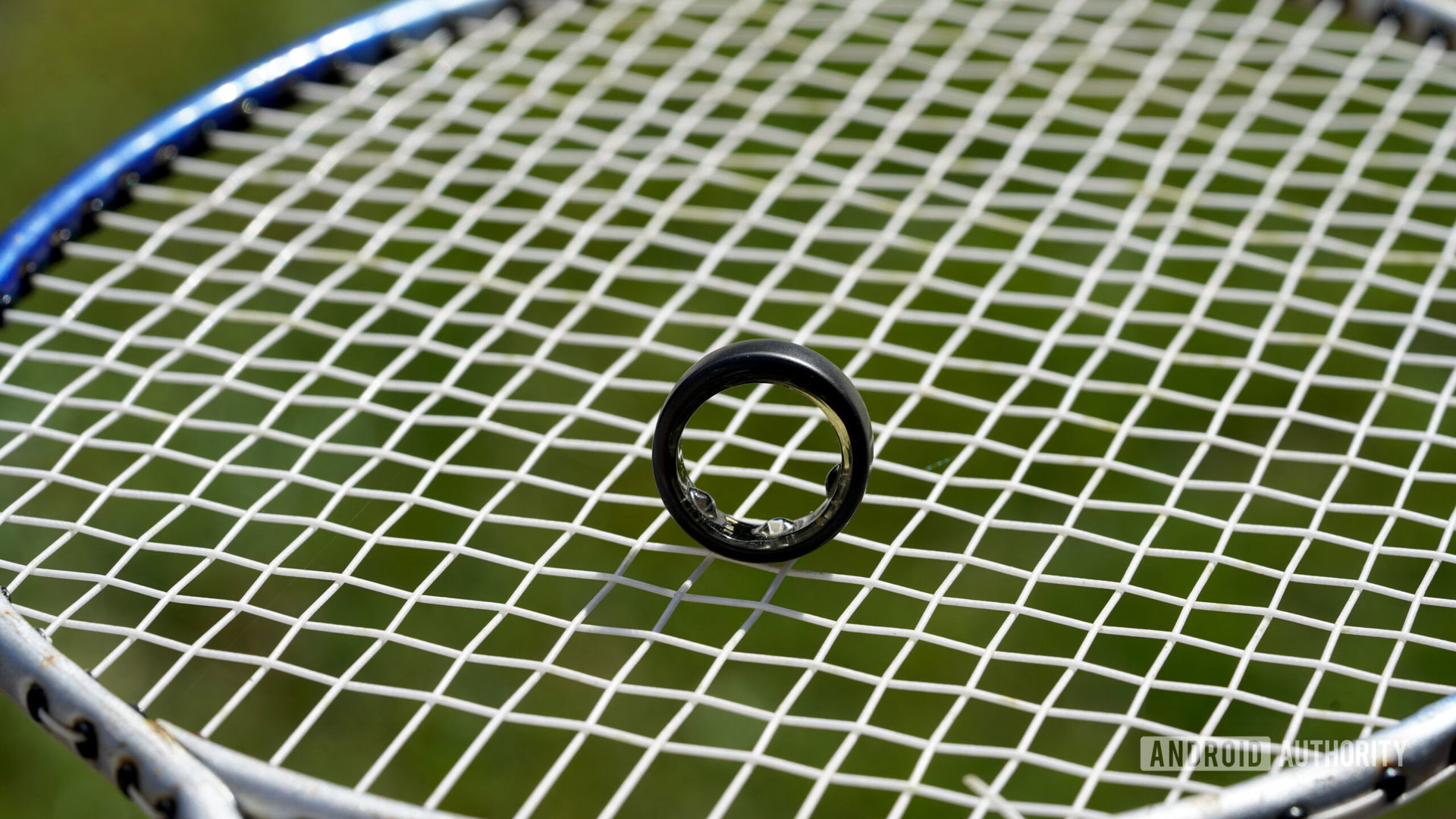 An Oura Ring stands upright on a badminton racket.