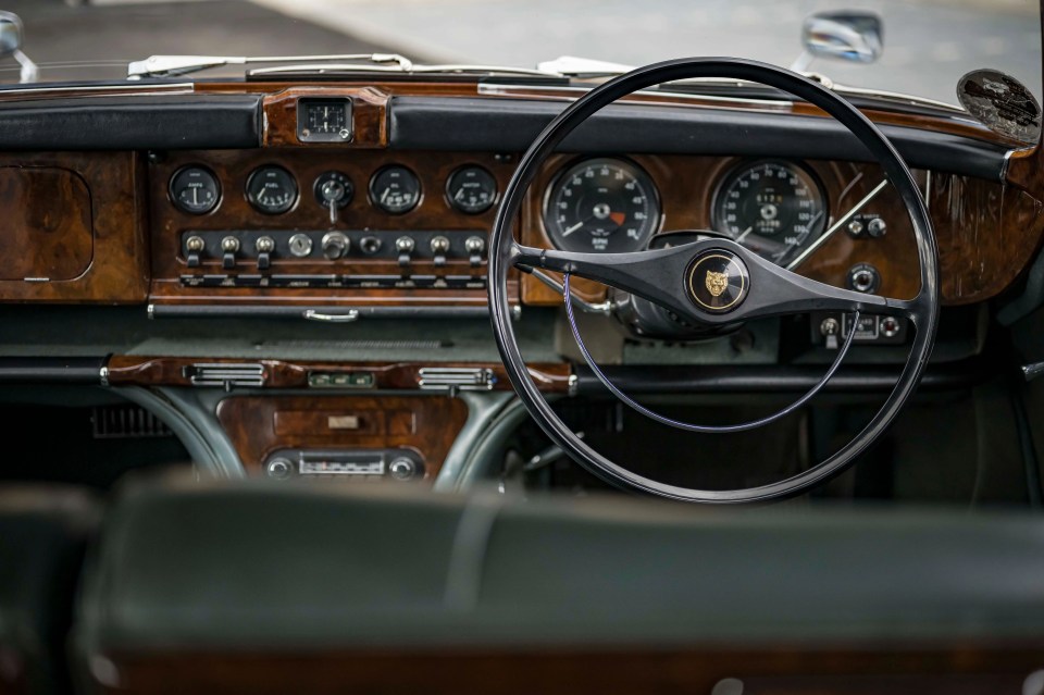 Interior view of a 1966 Jaguar 420G, featuring the steering wheel, dashboard, and instrument panel.