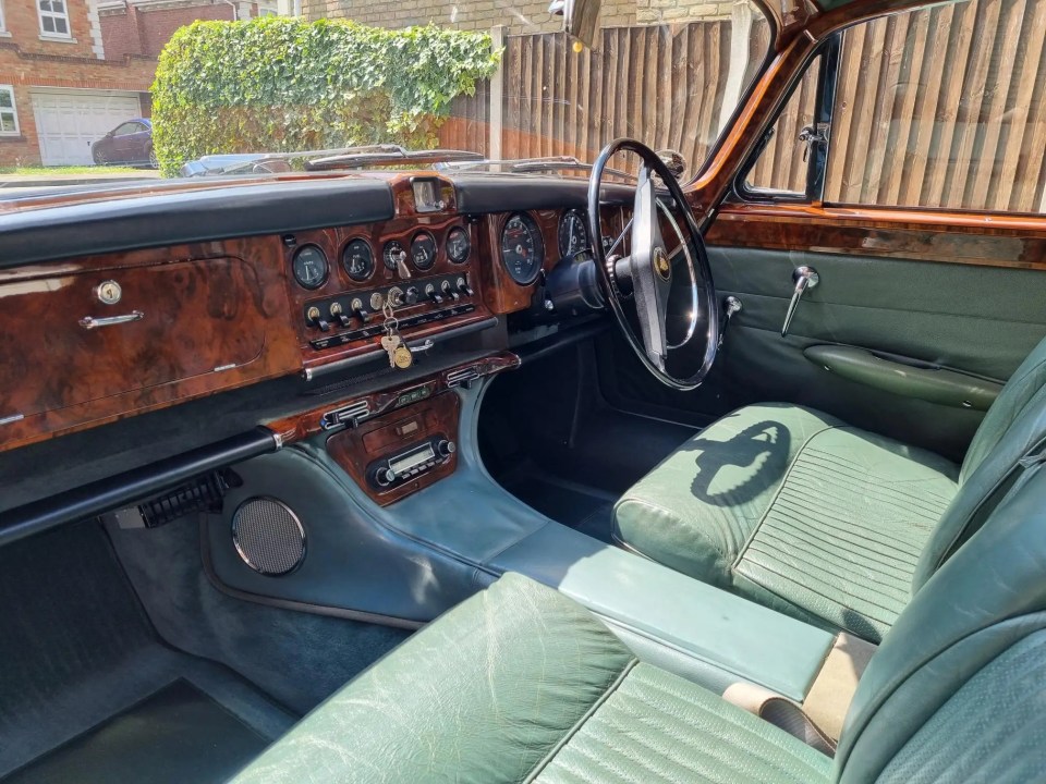 Interior of a restored 1966 Jaguar 420G, featuring green leather seats and a wood dashboard.