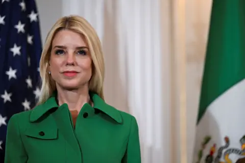 Reuters The attorney general in a green dress standing in front of flags