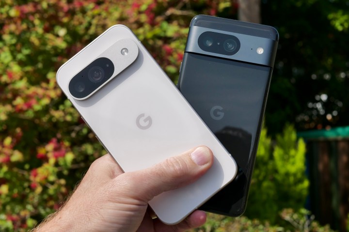 A person holding the Google Pixel 9 and Google Pixel 8.