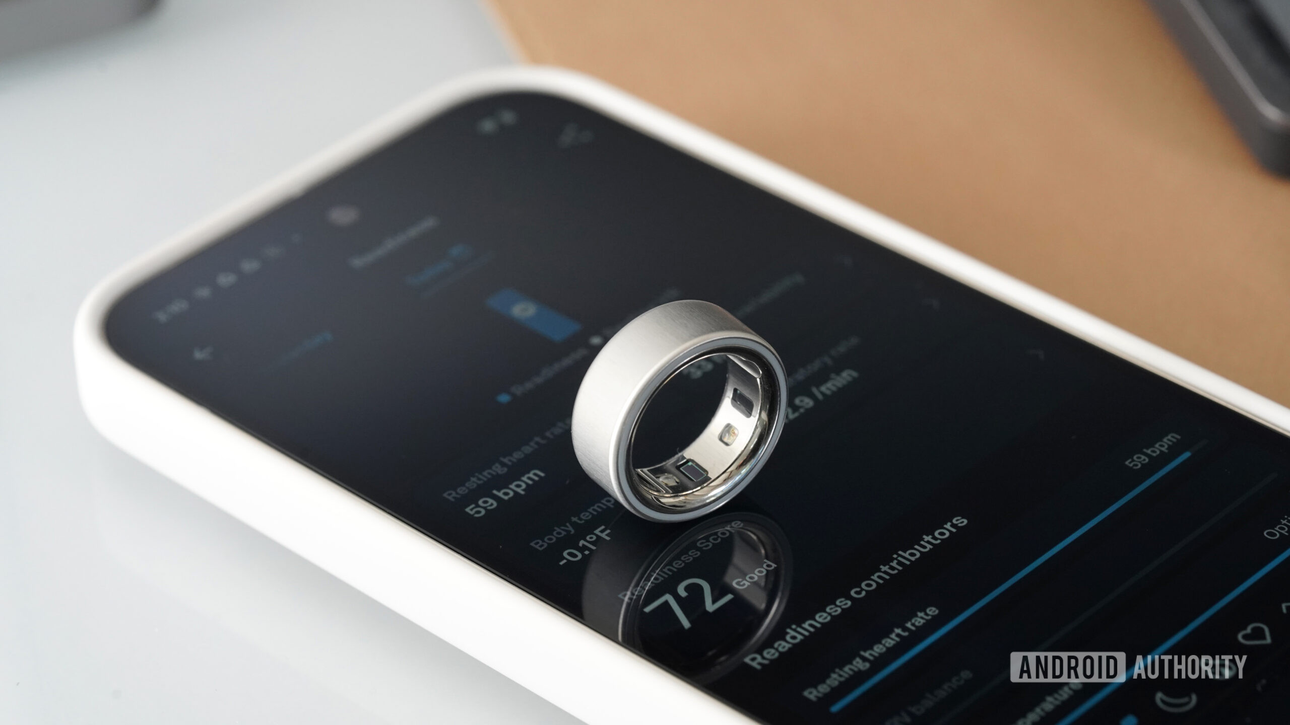 An Oura Ring 4 rests on a users Pixel 9.