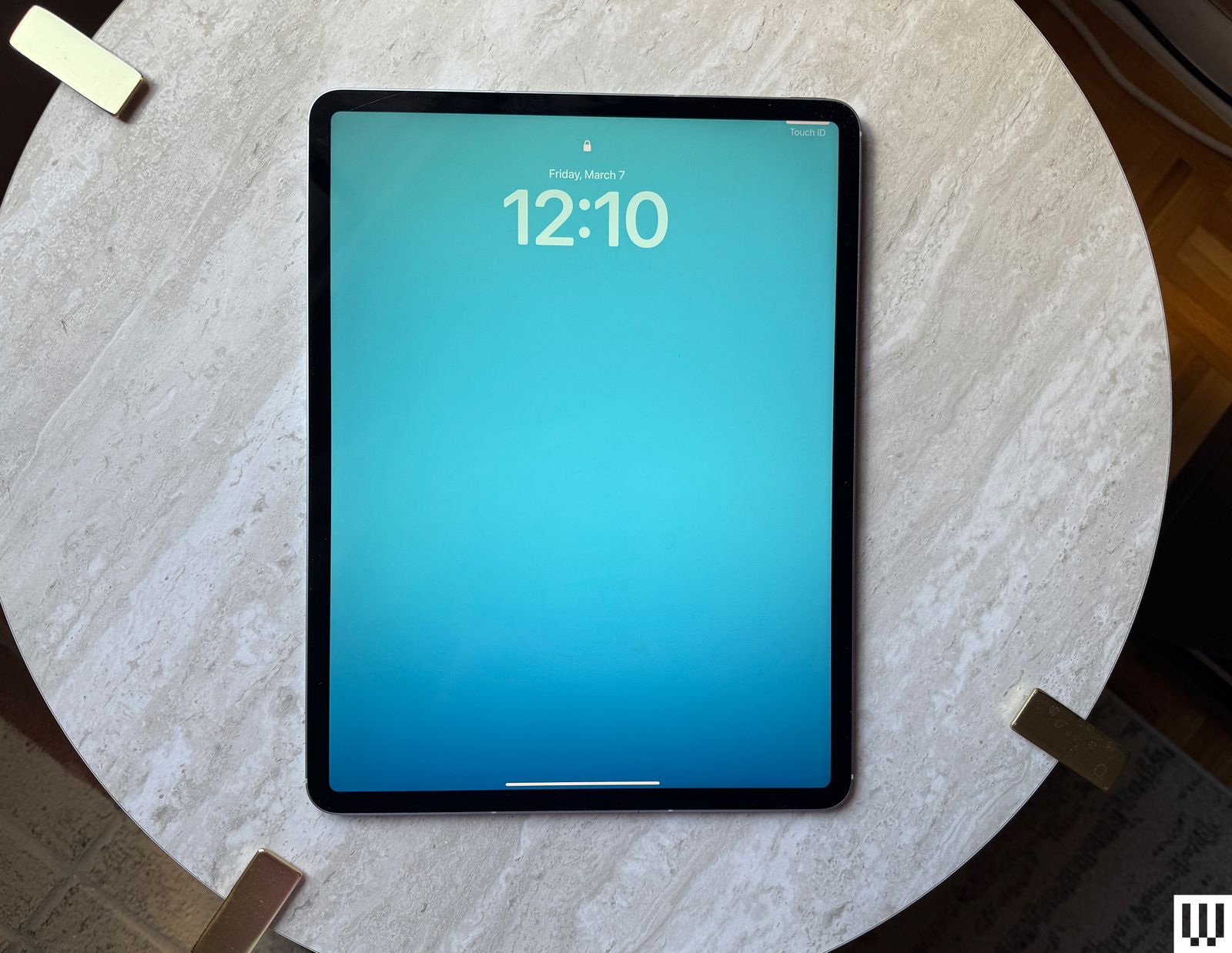 Overhead view of an Apple iPad Air M3 2025 sitting on a circular marble table with the screen showing the time and date