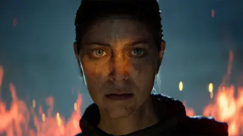 Ninja Theory Screenshot shows an incredibly life-like character staring impassively at the viewer as flames rage behind her. Marks and dirt on her face suggest she's recently been involved in some sort of fight