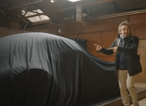 Richard Hammond pointing at a car covered by a sheet.