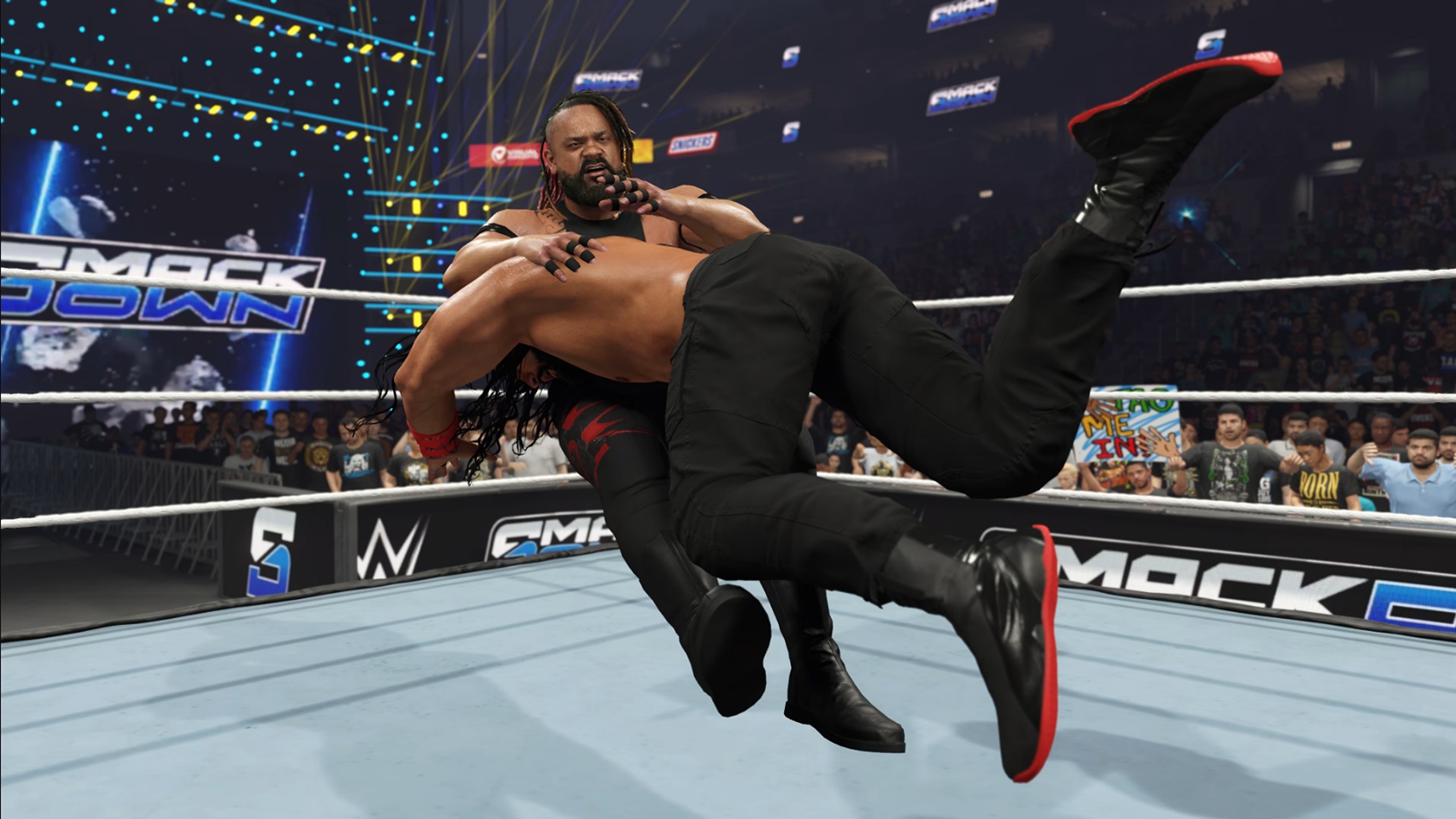 Promotional screenshot of Jacob Fatu getting speared by Roman Reigns in WWE 2K25