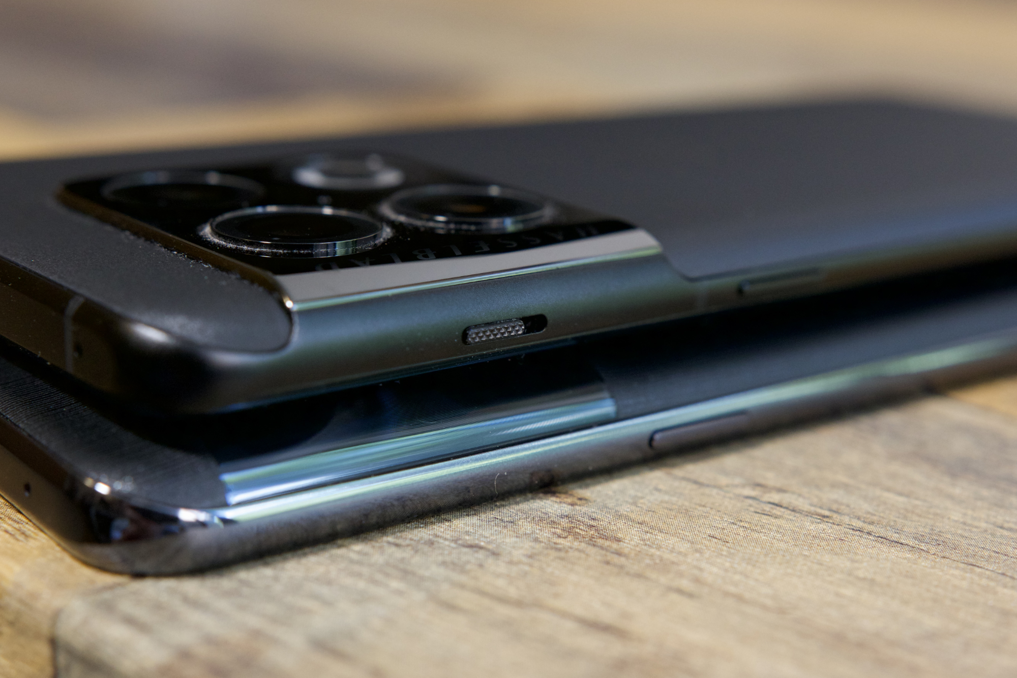 The OnePlus 10T and OnePlus 10 Pro lying a wood desk next to each other.