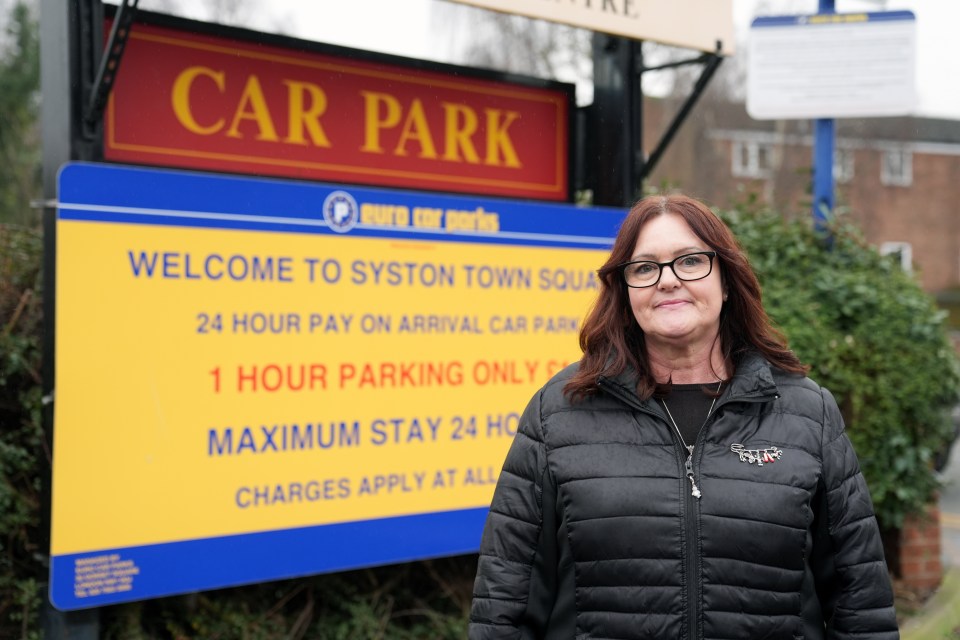 Woman standing in front of a car park sign.