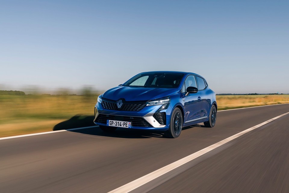 Blue Renault Clio driving on a road.