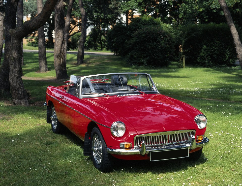 Red convertible parked on a grassy field.