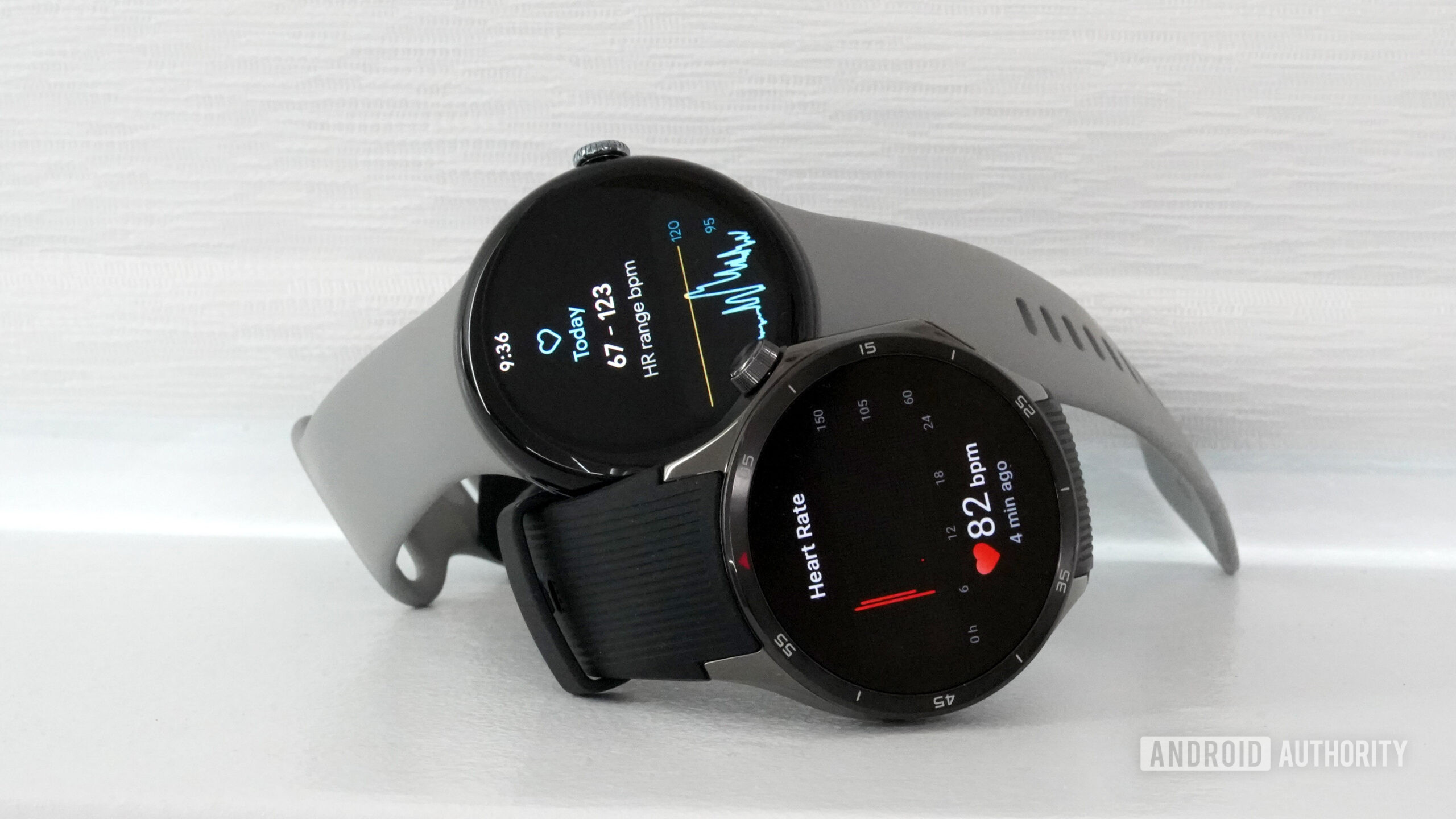 A Google Pixel Watch 3 and OnePlus Watch 3 rest on a shelf, each displaying heart rate data.